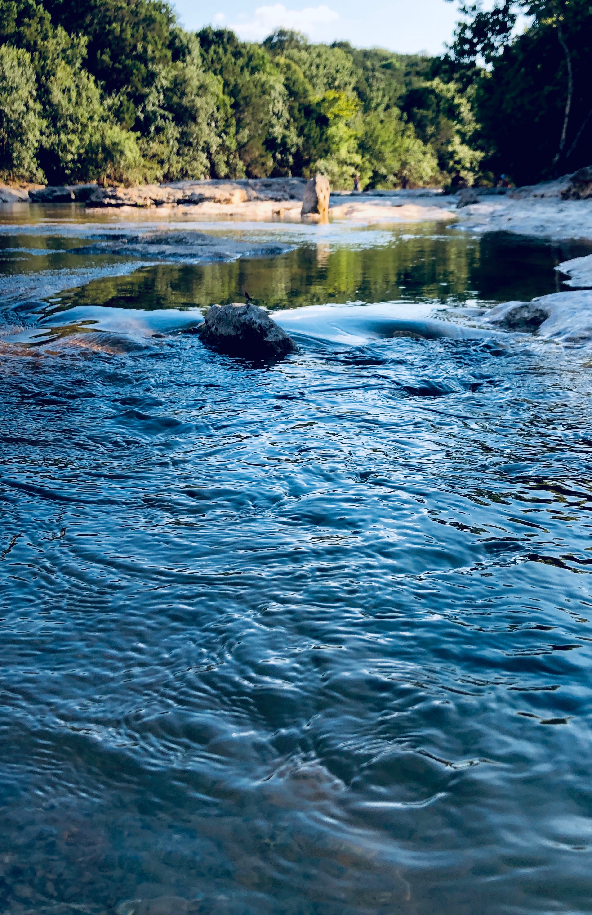 Shallow, moving water with trees in on the horizon.